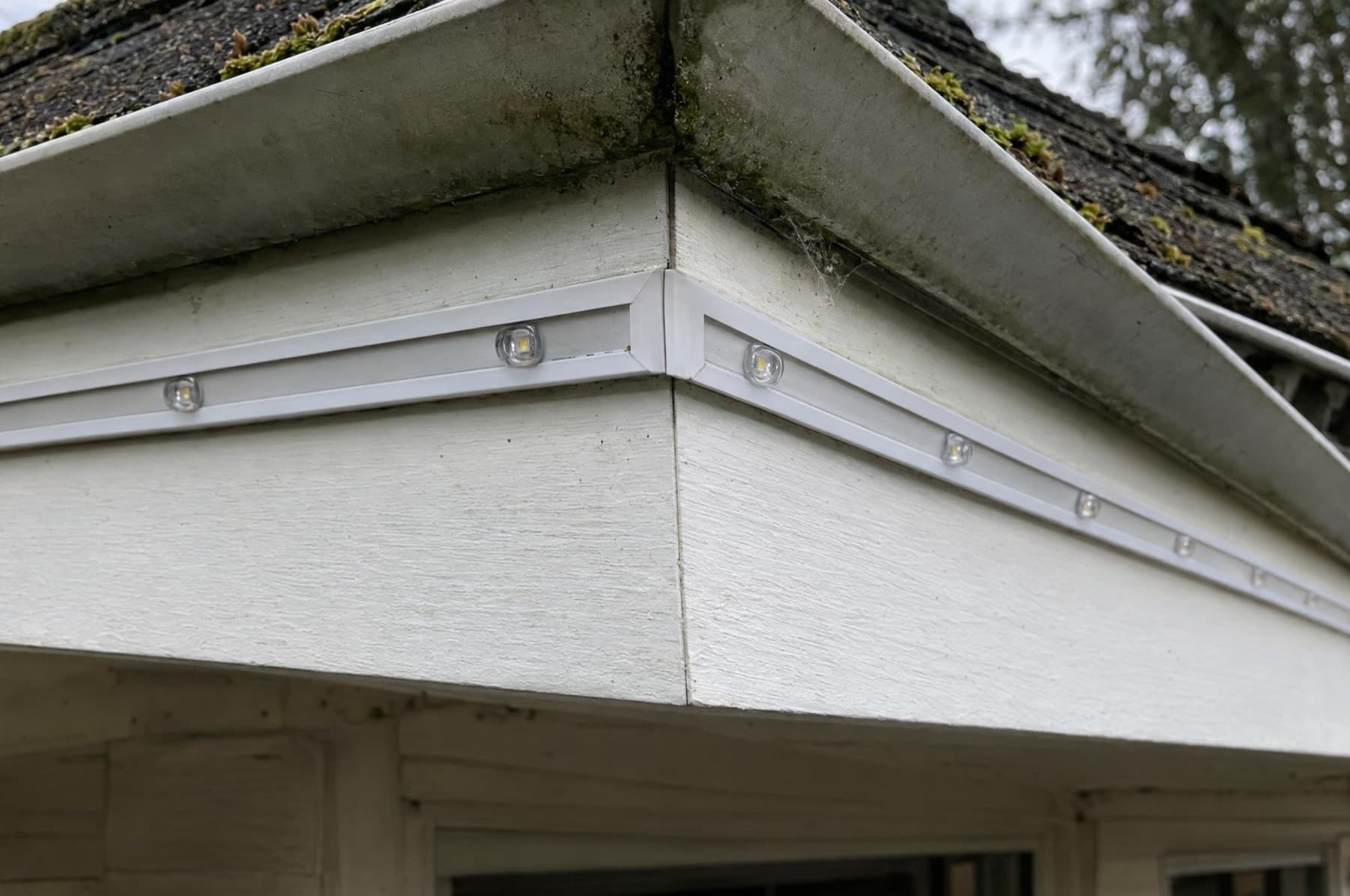 Daylight close-up of a mitered lighting-channel corner at a roof eave