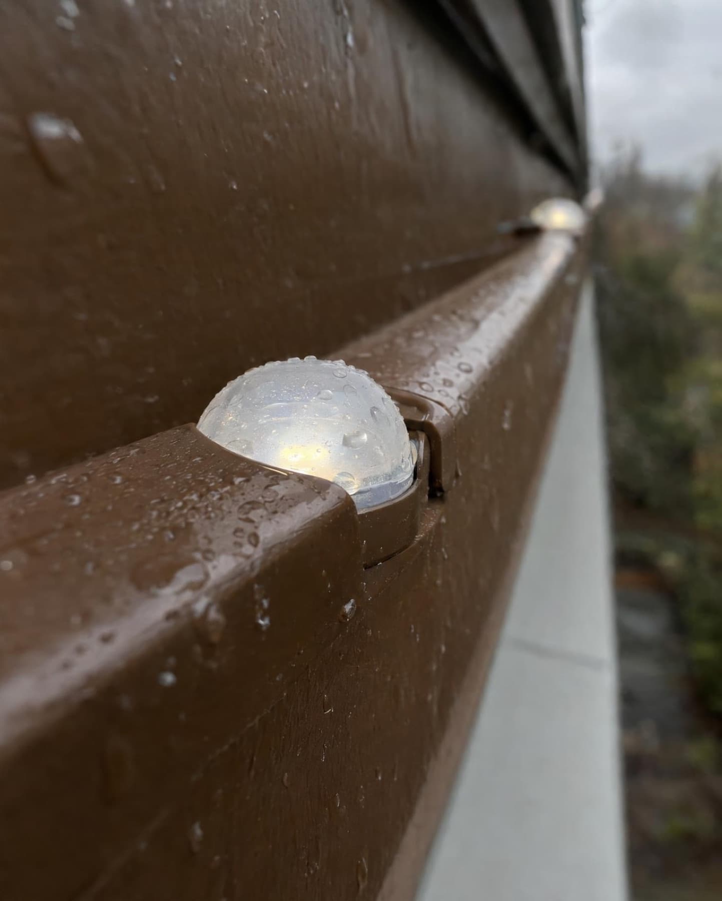 Macro of a single pebble light in a brown channel with rain droplets