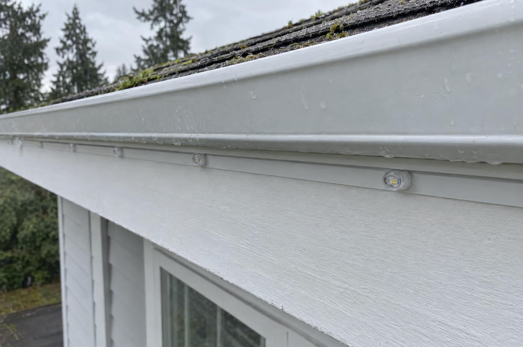 Daylight close-up of a white lighting channel on a white fascia under the gutter