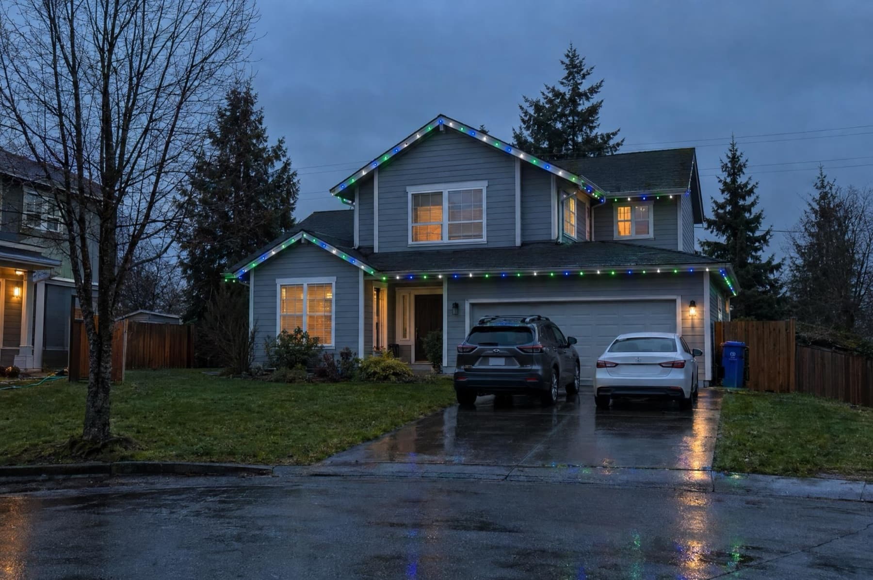 Two-story home on a cul-de-sac with navy, green and white roofline lights