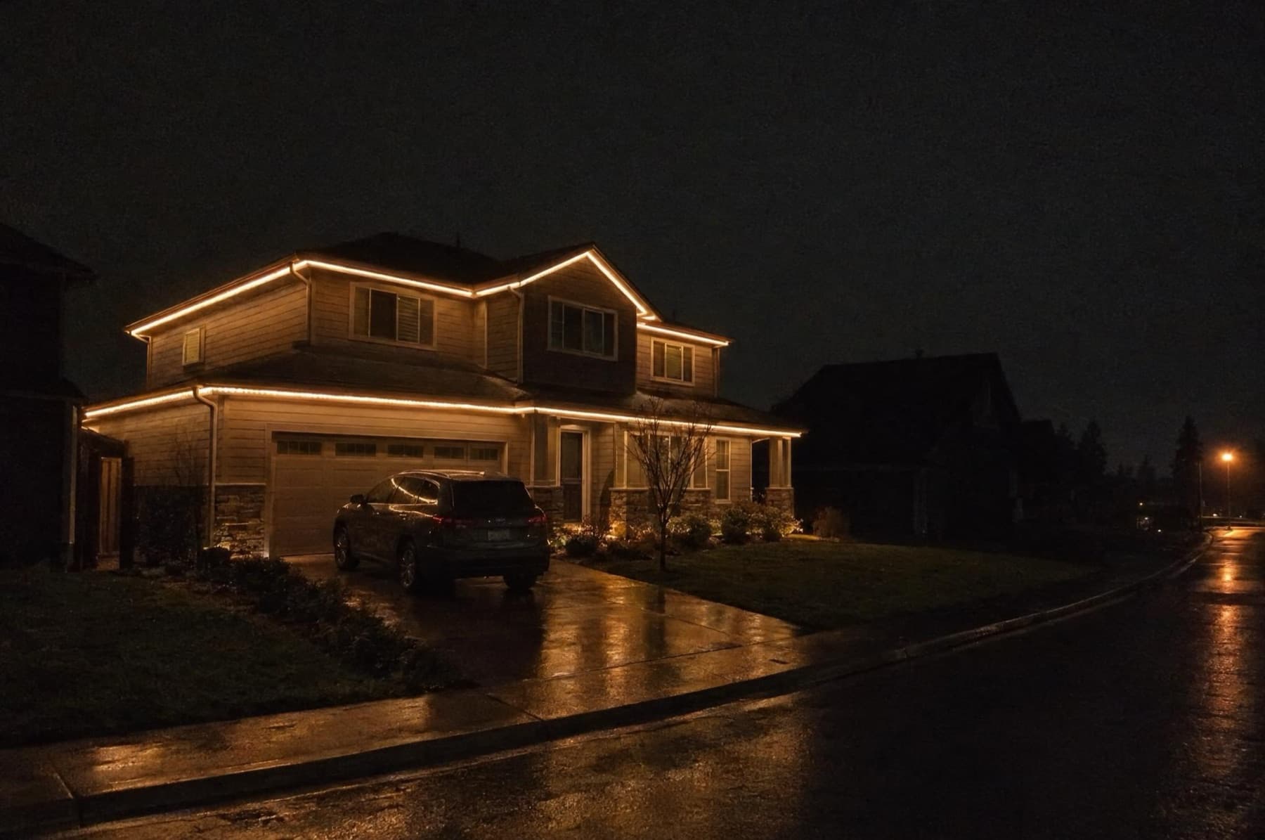 Two-story home late at night with a low warm-white glow around the whole roofline