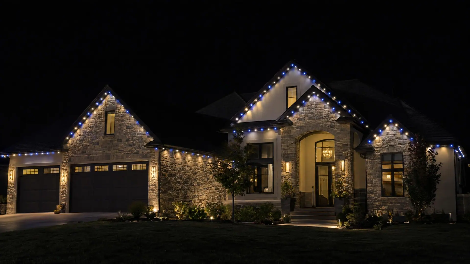 A home at night outlined in elegant cool white and sapphire blue roofline lights