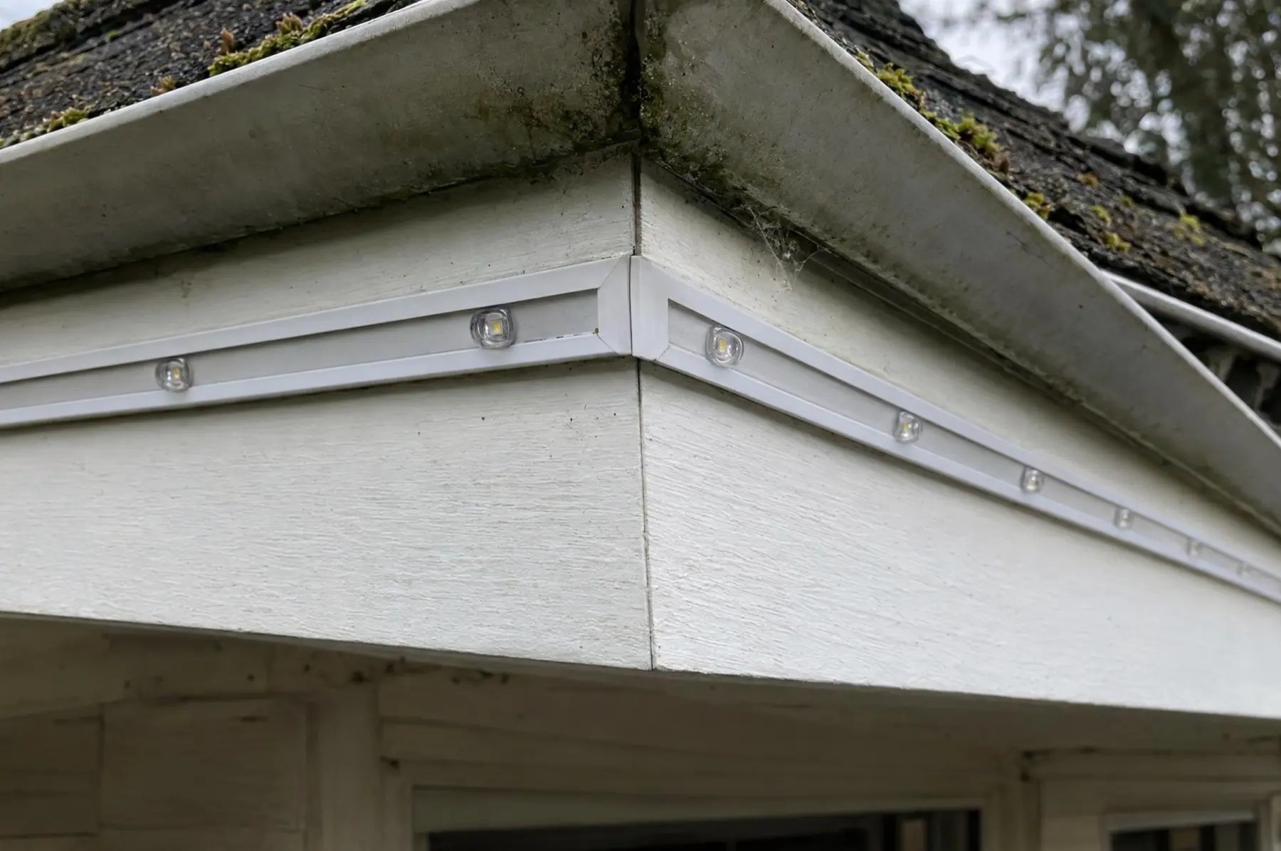 Daylight close-up of a mitered lighting-channel corner at a roof eave